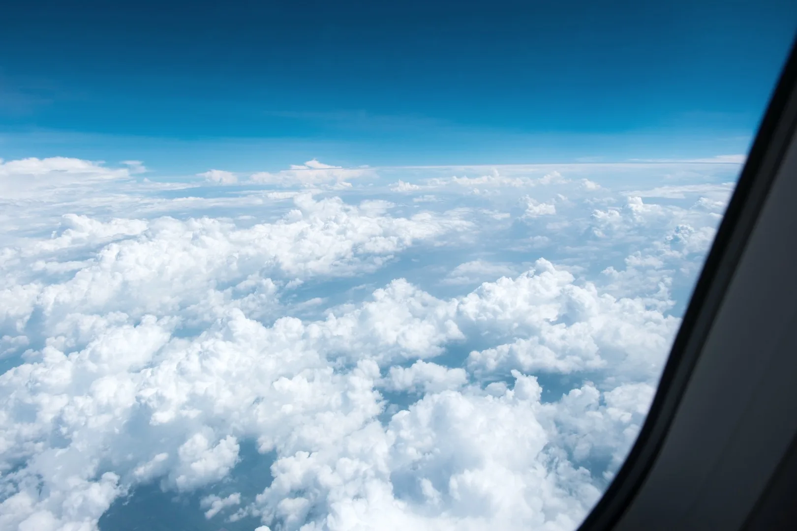 View through an airplane window showing clouds and sky during an international family relocation flight